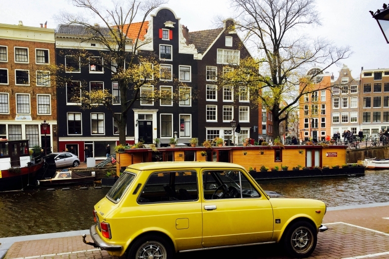 Yellow car parked in front of colorful town house and a stream