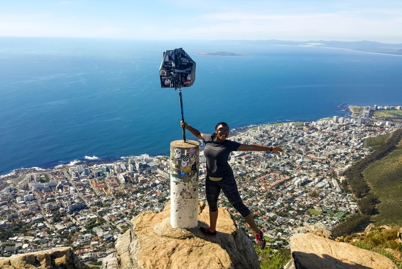 Jaela Cabrera McDonald '18 poses atop a boulder in Cape Town, showing the ocean and the city behind her