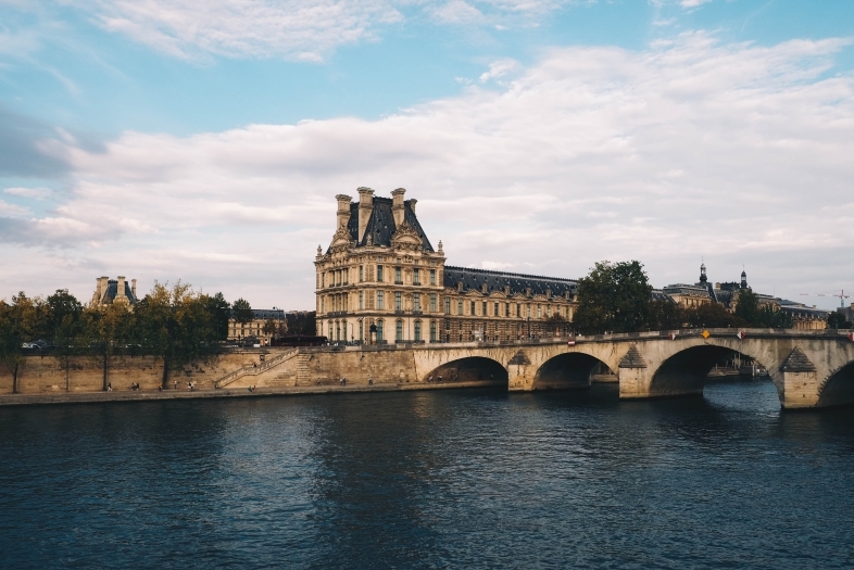 River meets a bridge with a french architecture building in the background