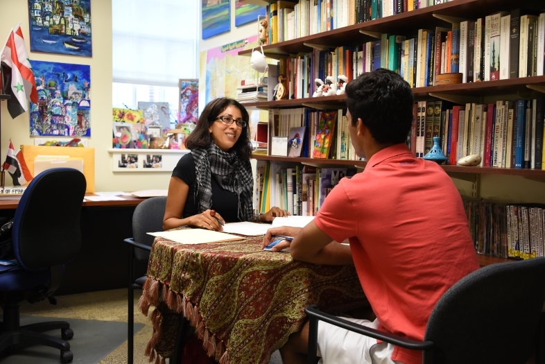 Professor and student talking while facing one another in her office