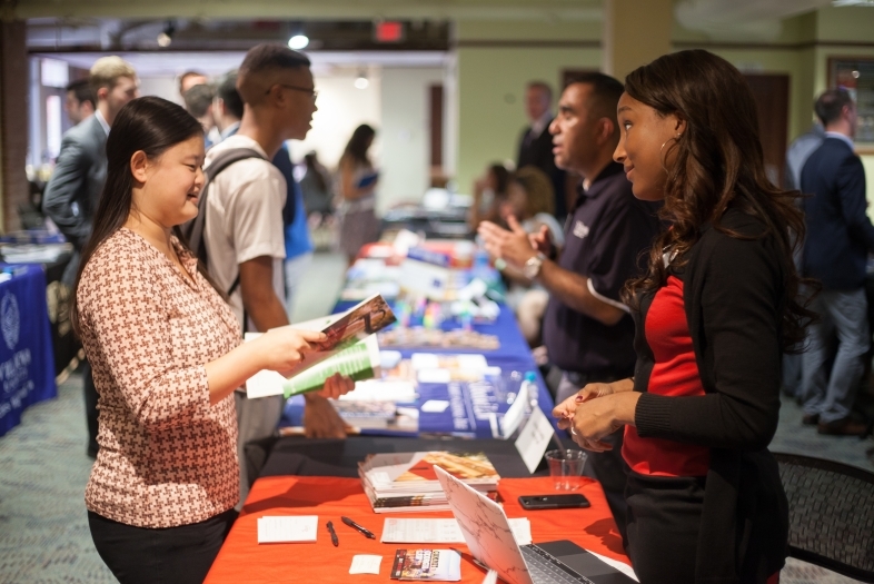 Recruiter talks to student at a booth at job fair