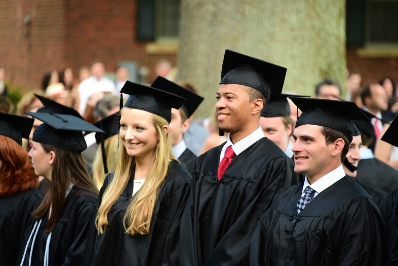 Students in cap and gown stand in a row