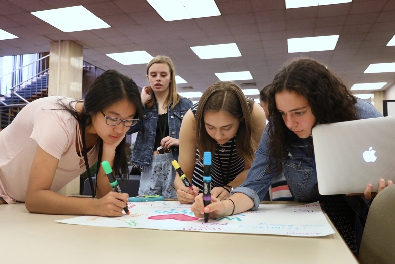 Kids from summer program work together on a poster