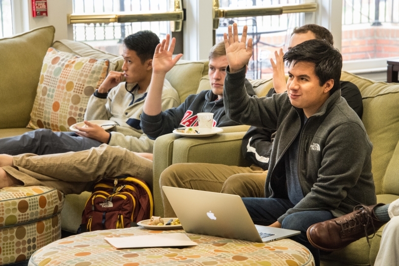 Students raise their hands while sitting on the couch at an event at Spencer Weinstein Center