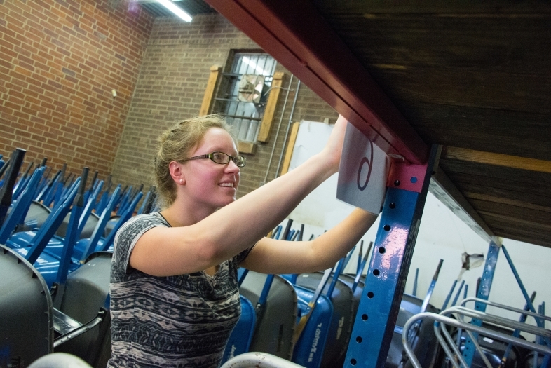 Student in community-based learning course helps organize a warehouse with a mathematical algorithm and hangs signs up in warehouse