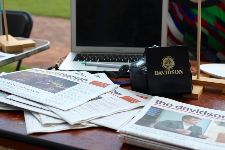 The Davidsonian copies on a table with a laptop and Davidson gear