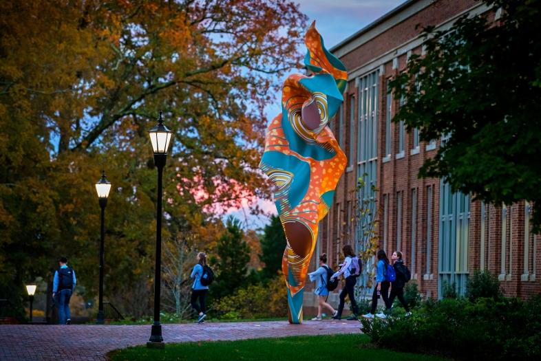 Students walk around the exterior of the Wall Center with Wind Sculpture in full view