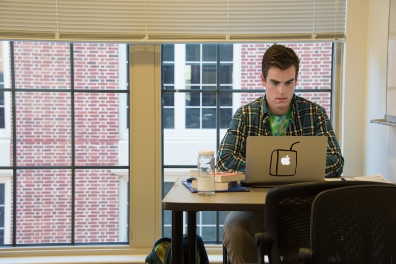 Study room of dorms where student does homework on his laptop