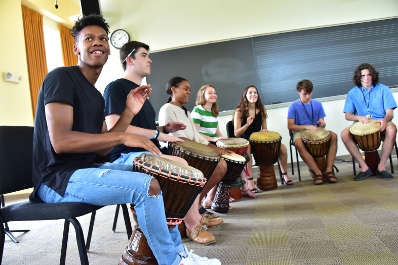 July Experience students drumming in big circle