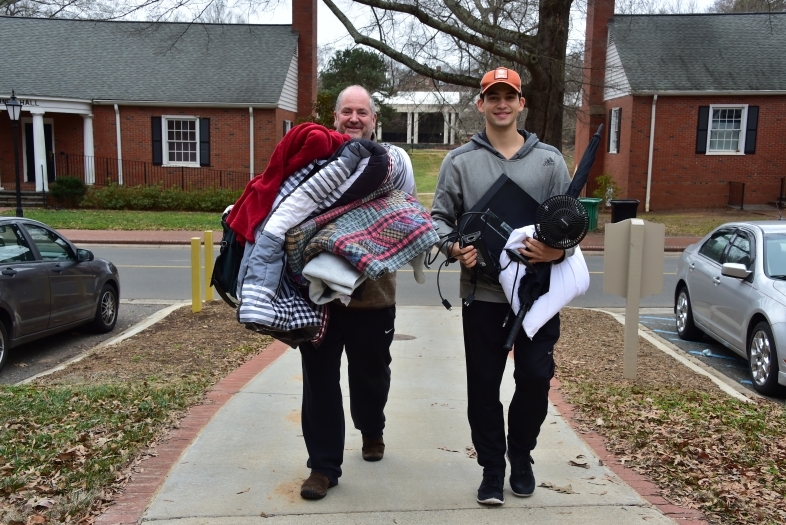 Student and family member carry arms full of items into dorm