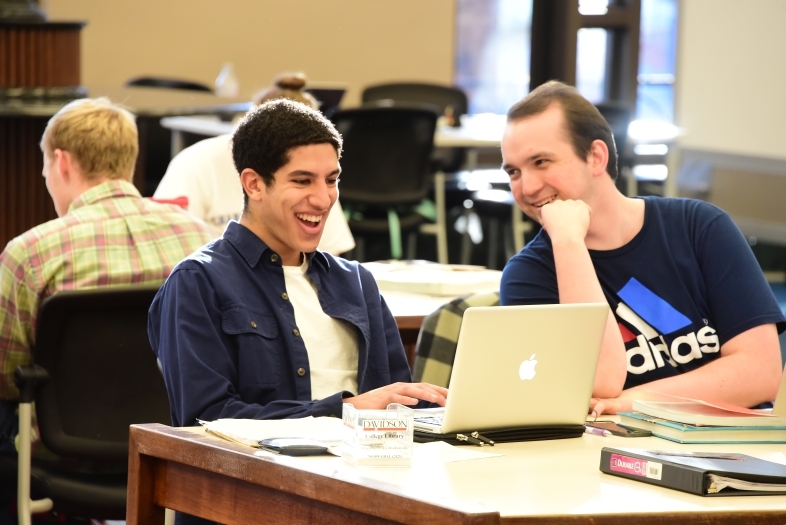 Students sit at table in the Library and study