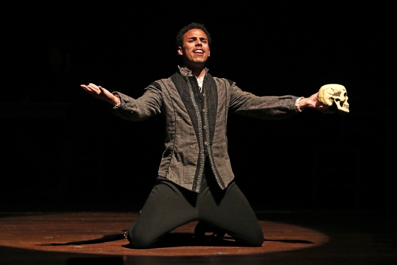 Performer on his knees sings a song while holding a skull