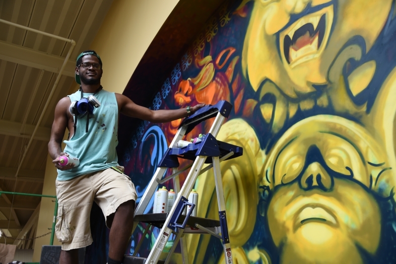 Stewy Robertson '15 with can of spray paint, working on mural