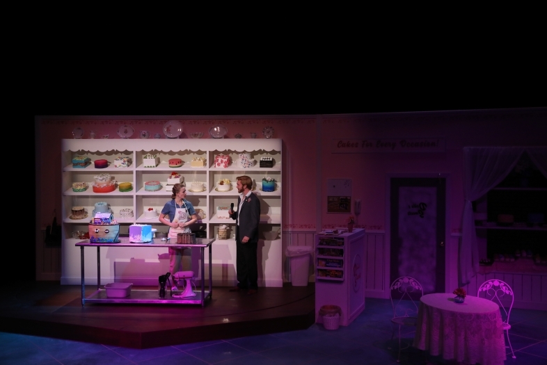 Actress standing in front of a giant display case full of decorative cakes