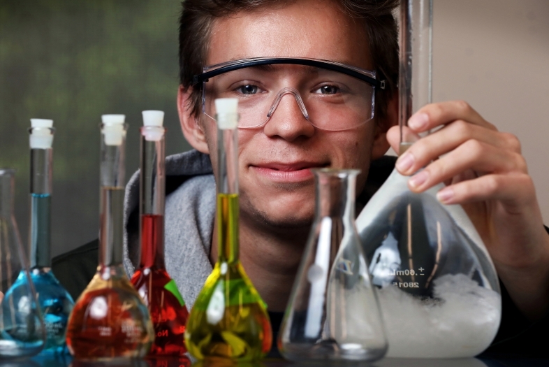 Student holding up beakers of various colors