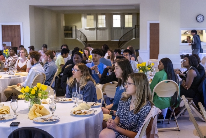 Students sitting at tables in reception space