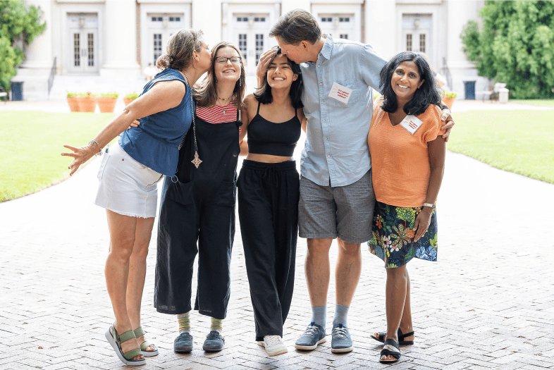 Parents and their students embracing outside and smiling