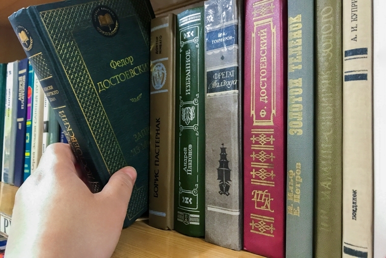 Hand reaching for a Russian language book on a shelf