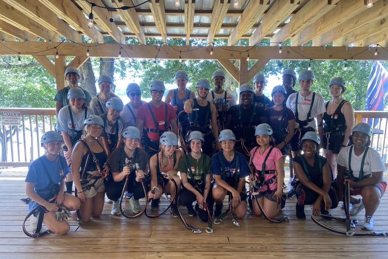 A group of students in harnesses and helmets smiling outside