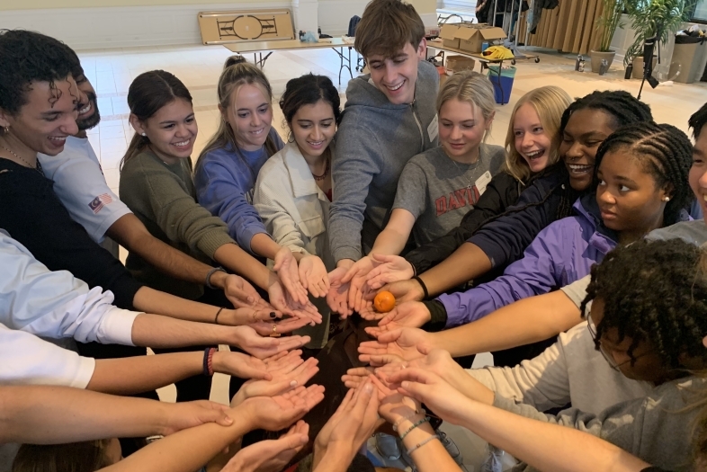 A group of students circled up with their hands in the middle