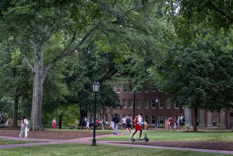 Students walking on campus with green trees in background