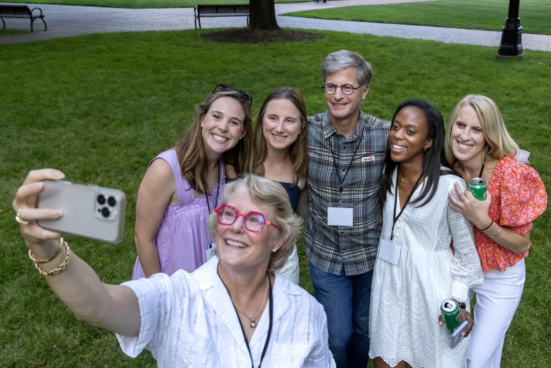 a group of alums pose to take a selfie together outside