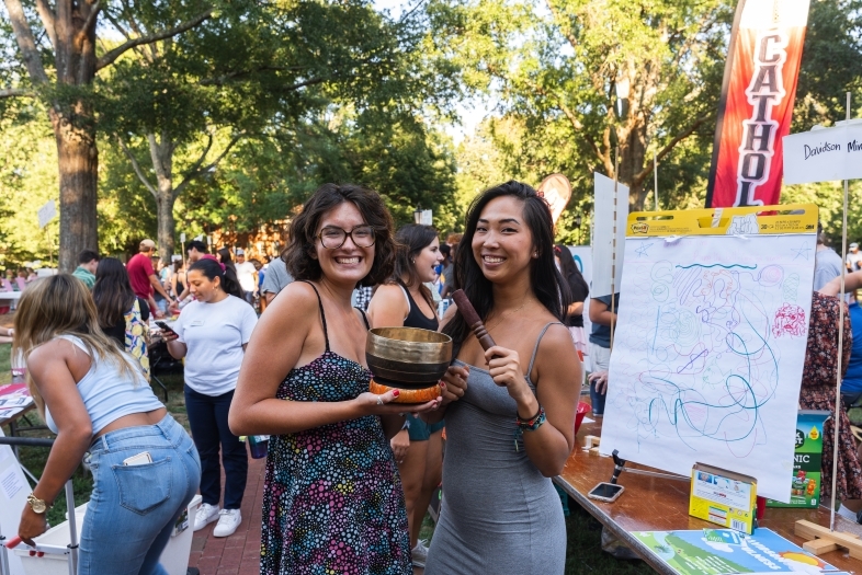 two young women standing at an activities fair smiling