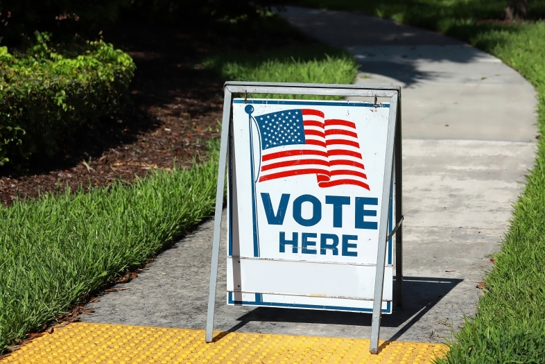 "Vote Here" sign in front of a sidewalk