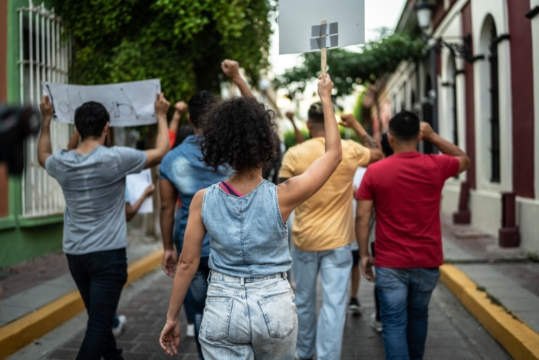 a group of young people holding signs and marching in a street