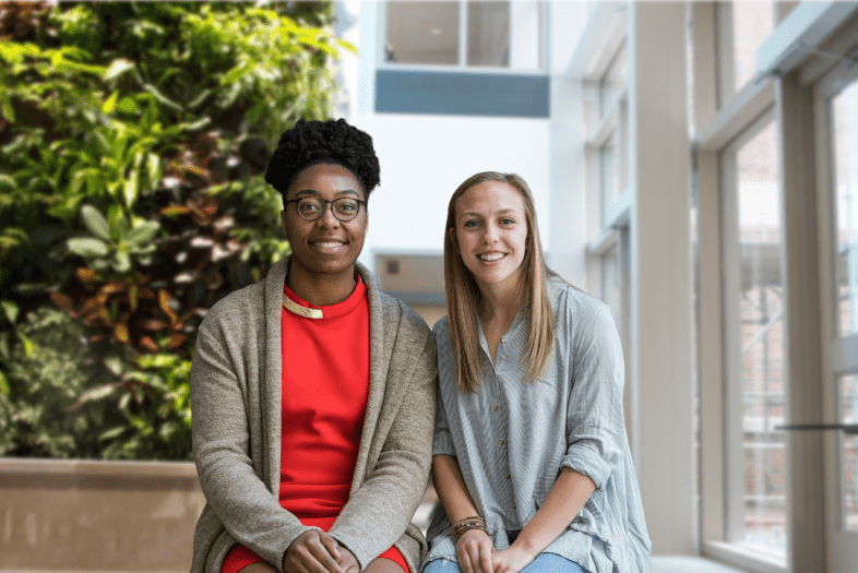 a young Black woman and a young white woman sit together