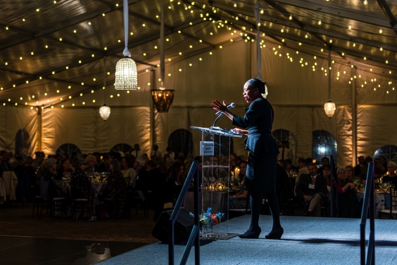 50+ Years of Coeducation speaker at podium in lighted tent