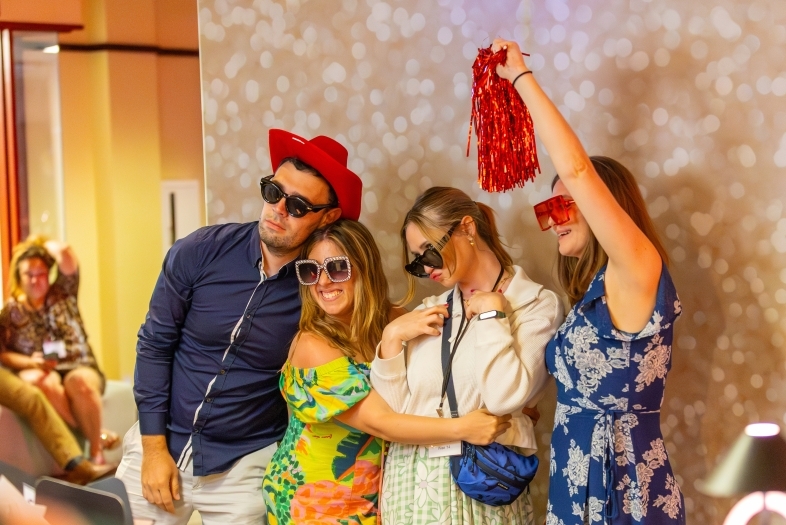 a group of young people take a silly picture in front of a photo booth