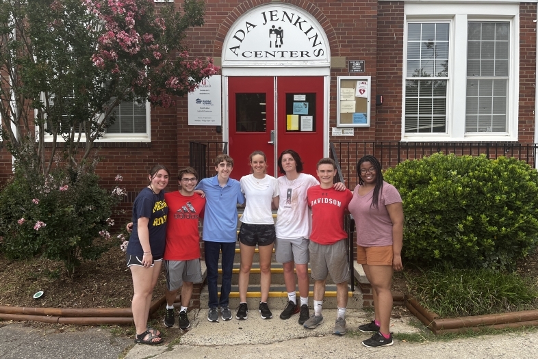 a group of students standing together in front of a brick building that reads "Ada Jenkins Center"