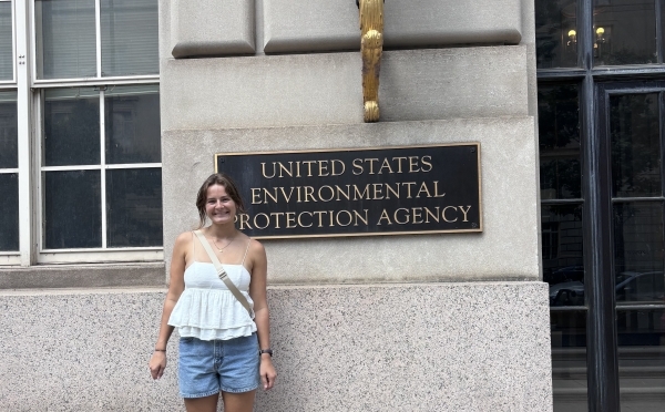 a young white woman stands in front of "US EPA" sign