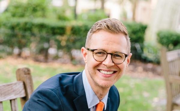 a young white man wearing glasses and suit and tie