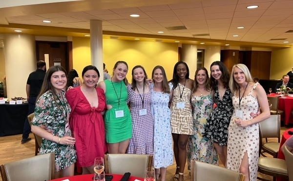 a group of young women in dresses and nametags smile standing together