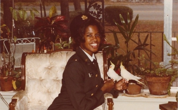 a young Black woman in uniform sitting on a white chair