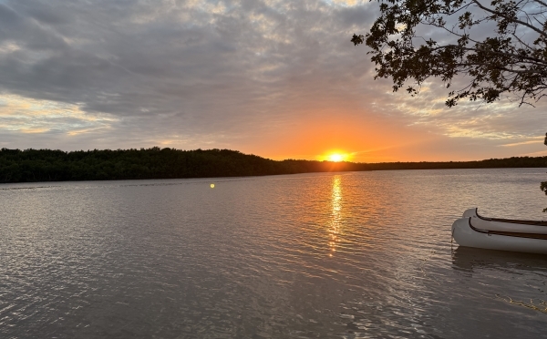 a body of water at sunset with a canoe in the foreground