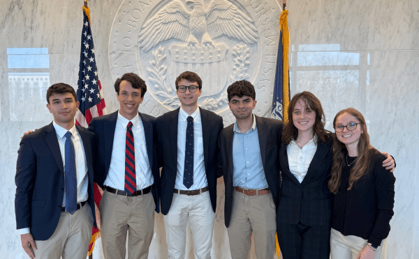 a group of six young people standing in front of the federal reserve building