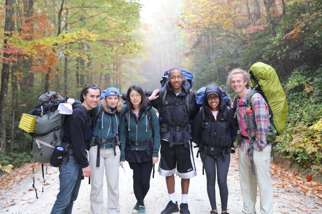 Students backpack with camping gear in the mountains with fall foliage 