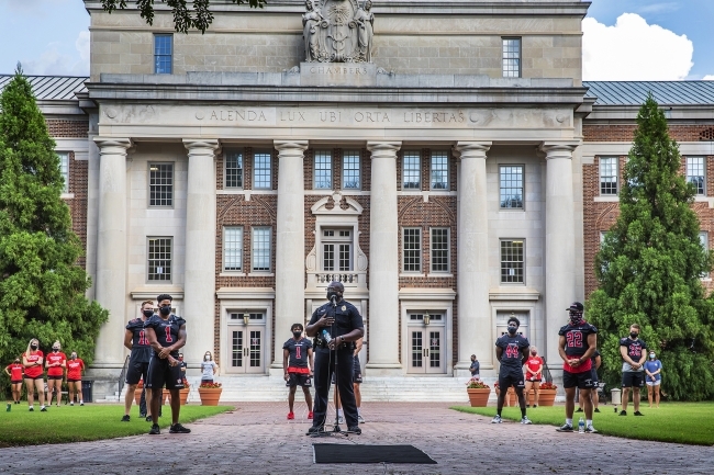 Social Justice Event - football players and campus police officer in front of Chambers