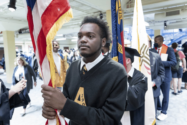 Students holding flags lined up outside of Duke Family Performance Hall 