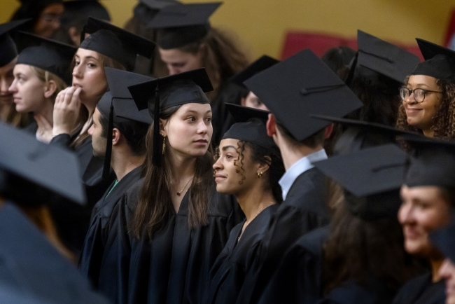 crowd of students in cap and gowns inside the Duke Family Performance Hall for convocation