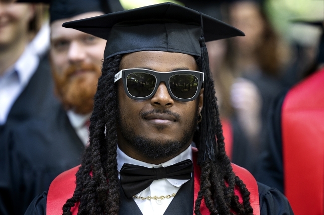 graduate in sunglasses and cap and gown