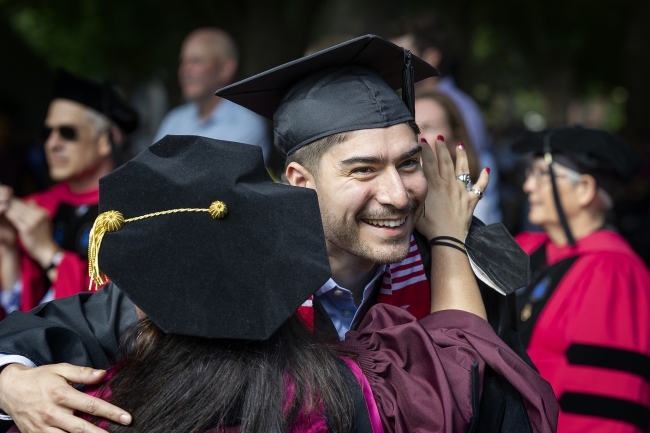 faculty member hugs graduate at commencement 