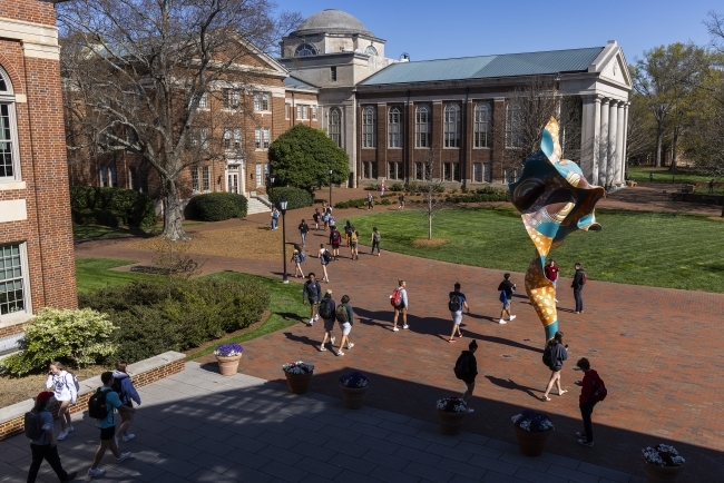 Students walking on campus with Shonibare statue and Chambers building