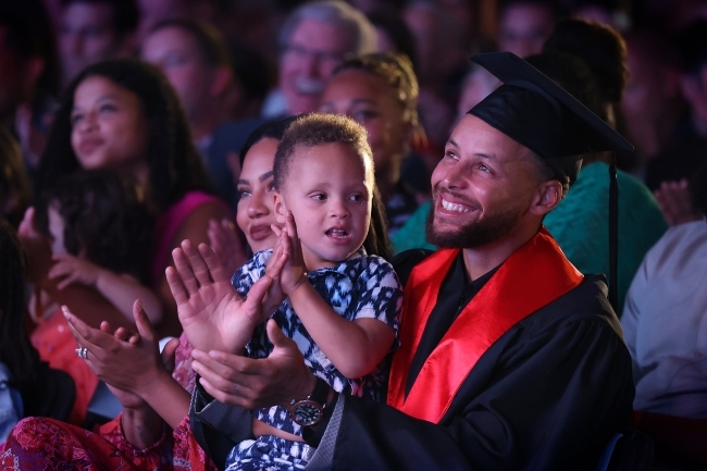 Stephan Curry applauds with his young son in lap