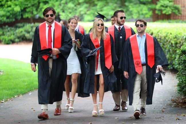 Group of students in commencement regalia walking and smiling