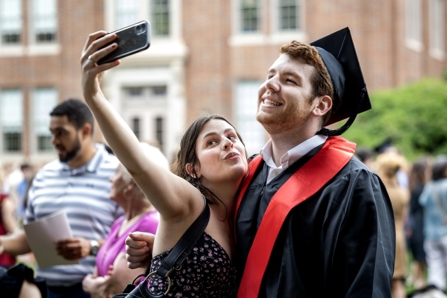 Student in cap and gown takes selfie