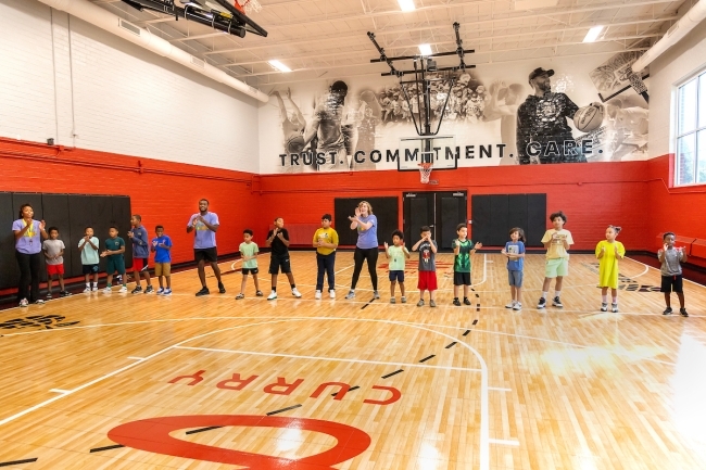 Students in a gym standing on basketball court